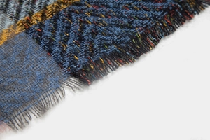 Macro shot of dark blue herringbone weave scarf with colorful flecks and frayed fringe