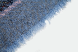 Close-up of herringbone weave pattern on blue plaid scarf with fringe detail