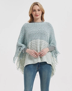 Close-up of the striped knit poncho featuring elegant long fringe detailing on the hem