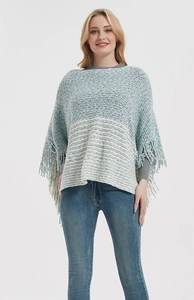 Detail of coarse knit poncho featuring blue and grey gradient stripes and fringe hem
