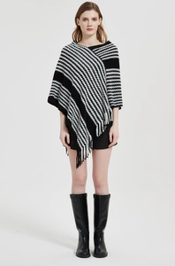 Detail eines schwarz-weißen Strickponchos mit geometrischen Mustern und Fransensaum