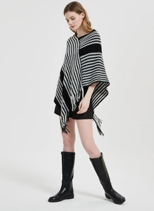 Detail eines schwarz-weißen Strickponchos mit Hahnentrittmuster und Fransenbesatz