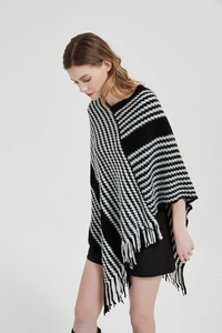 Nahaufnahme des schwarz-weißen Strickponchos mit Hahnentritt-Muster und Fransen-Details