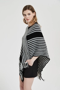 Details eines Strickponchos mit schwarz-weißen Streifen und Hahnentrittmuster mit Quasten