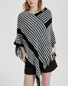 Detail eines schwarz-weißen Hahnentritt-Ponchos mit weichem Strickmuster und Fransenkante