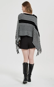 Rückansicht eines Strickponchos mit schwarz-weißen Hahnentrittstreifen und Fransen