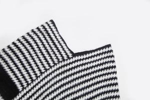 Detailansicht der weichen schwarz-weißen Hahnentritt-Strickstruktur auf dem Poncho