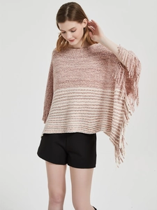 Detail of pink and beige striped knit poncho featuring elegant long fringe hem accents