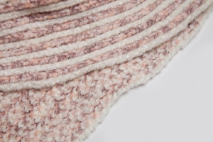 Detailed close-up of thick chenille knit fabric in striped pink and cream white tones