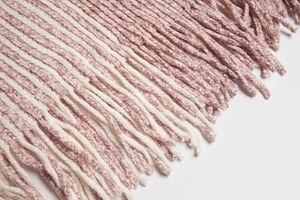 Macro detail of soft knit shawl edge with pink and white stripes and thick tassel fringe