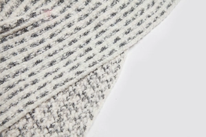 Detailed close-up of thick ribbed knit fabric in striped cream and charcoal grey