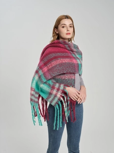 Detail of oversized plaid scarf with long tassels in fuchsia and green knit fabric