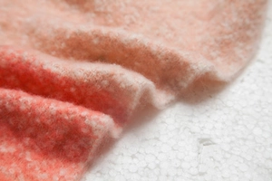 Macro-detail van zacht oranje en roze kleurverloop breigoed met dikke franjes textuur