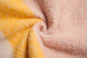 Detailopname van dikke mohair textuur met roze en gele kwastjes op de sjaal