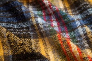 Close-up of thick plaid fabric texture featuring yellow and blue wool blend weave