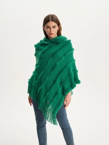 Detailed knit texture of green hooded poncho featuring fringe tassels and plush stripes