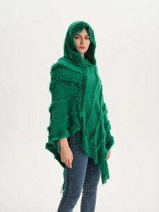 Detail of dark green hooded knit poncho with faux fur trim and long tassel fringe