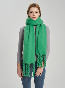 Detail of grass green knitted scarf featuring chunky twisted tassels and wool texture