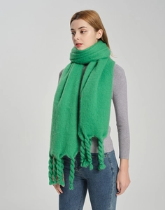 Detail of chunky twisted tassels on a thick green knit scarf for winter warmth