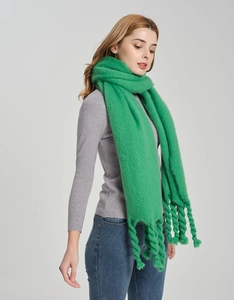 Close-up of bright green knit scarf with thick twisted tassels and soft texture