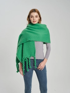 Close-up of chunky twisted rope tassels on a thick green knit scarf with mohair texture