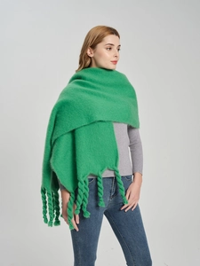 Close-up of vibrant green knitted shawl featuring thick braided tassels and mohair texture