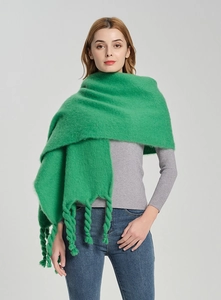 Detail of vivid green chunky knit scarf featuring unique braided tassels and fuzzy texture
