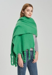 Detail of vibrant green knit shawl showing twisted tassel fringe and plush texture