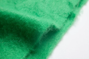 Detailed macro view of vibrant green boucle knit fabric with soft fiber texture