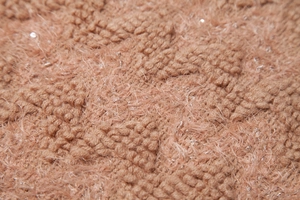 Macro detail of rose pink knit fabric with sequins and soft textured fringe trim