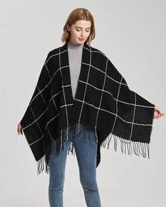Detail of black and white checkered knit shawl showing tassel hem and soft fabric texture