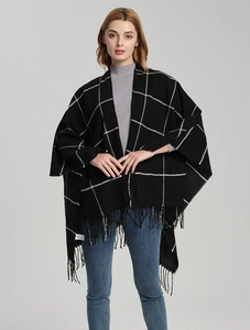 Close-up of black and white plaid knit shawl featuring elegant long tassel trim details