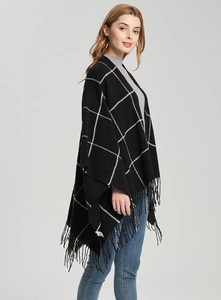Detail shot of black and white plaid shawl featuring long fringed tassels and soft knit texture
