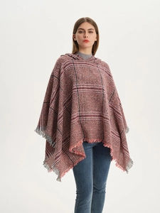 Detail eines rot-schwarzen karierten Strickponchos mit klassischen Fransen und Kapuze