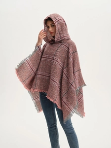 Detail eines weichen roten Karo-Ponchos mit Strickstruktur und feinen Fransenrändern