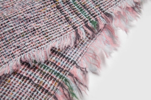Nahaufnahme von rosa kariertem Strickstoff mit Fransen am Kapuzenponcho-Schal
