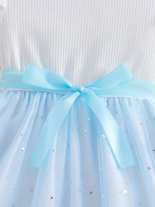 Detail of baby girl dress showing white ribbed bodice and blue star tulle skirt with bow