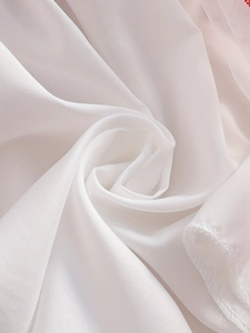 Détail macro de l'ourlet et des coutures en tissu blanc soyeux d'une robe pour fille