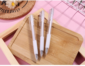 Detail of three transparent gel pens with white soft grips on a wooden tray