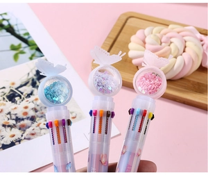 Close-up of butterfly multicolor ballpoint pens with sequins on a soft pink background