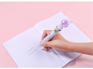 Close-up of hand writing with a multi-color ballpoint pen featuring purple sequins and a butterfly