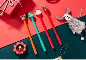 Detail of four Christmas gel pens with Santa, reindeer, and tree toppers in festive setting