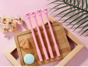 Gros plan de stylos gel cochon rose sur un plateau décoratif avec papeterie