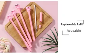 Gros plan de stylos gel cochon rose avec recharges d'encre sur plateau en bois