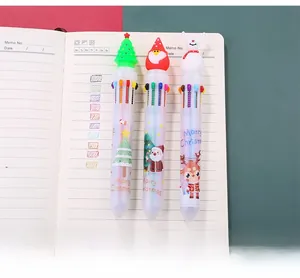 Detail of 10-color Christmas ballpoint pens with Santa and reindeer caps on a notebook