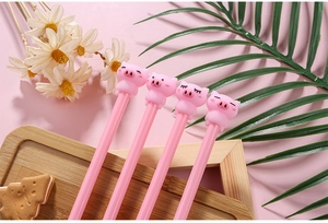Détail de quatre stylos à motif cochon rose avec expressions mignonnes sur un plateau
