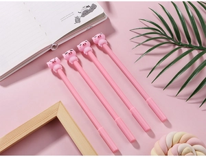 Gros plan de quatre stylos gel roses motif cochon mignon sur fond de papeterie