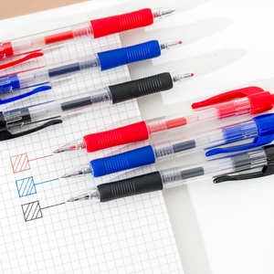 Set of 6 retractable gel pens in red blue black colors on white grid notebook
