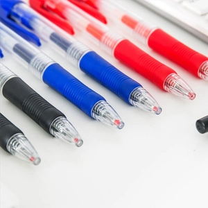 Transparent retractable gel ink pens in black blue and red set on white desk