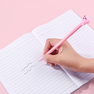 Stylo gel cochon rose mignon utilisé pour écrire sur un cahier à lignes